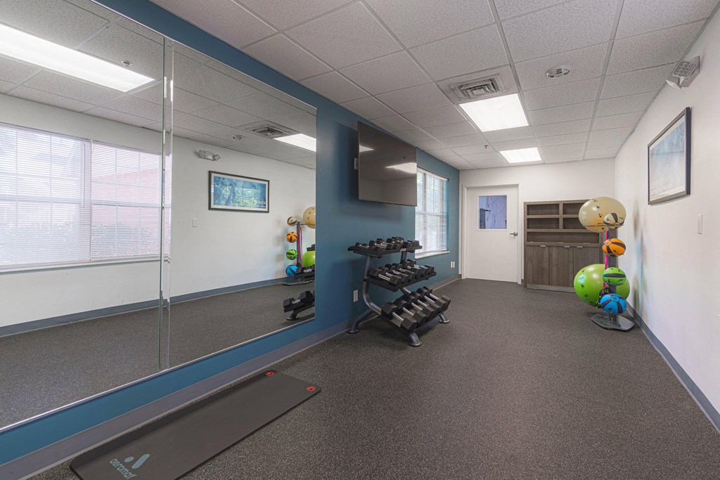 a workout room with weights and a treadmill in the corner of a room